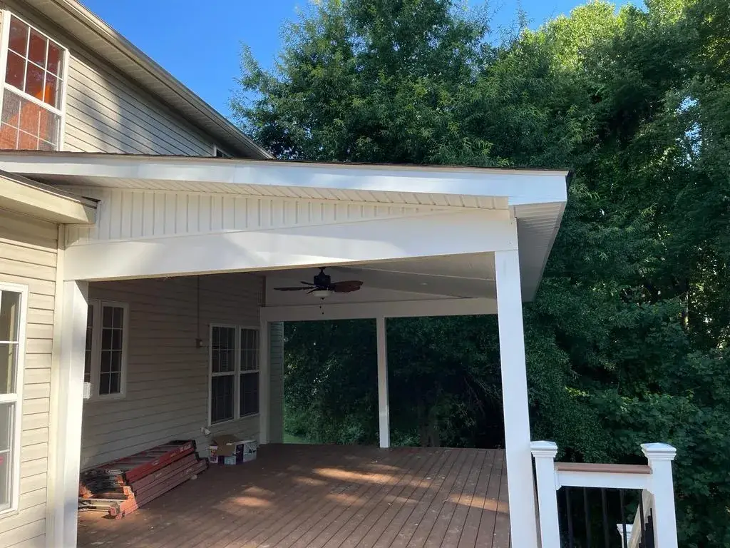 A detached shed with a green standing seam metal roof.