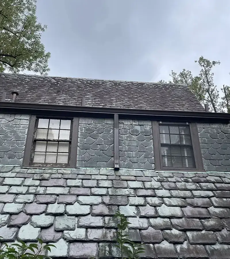 A detached shed with a green standing seam metal roof. 