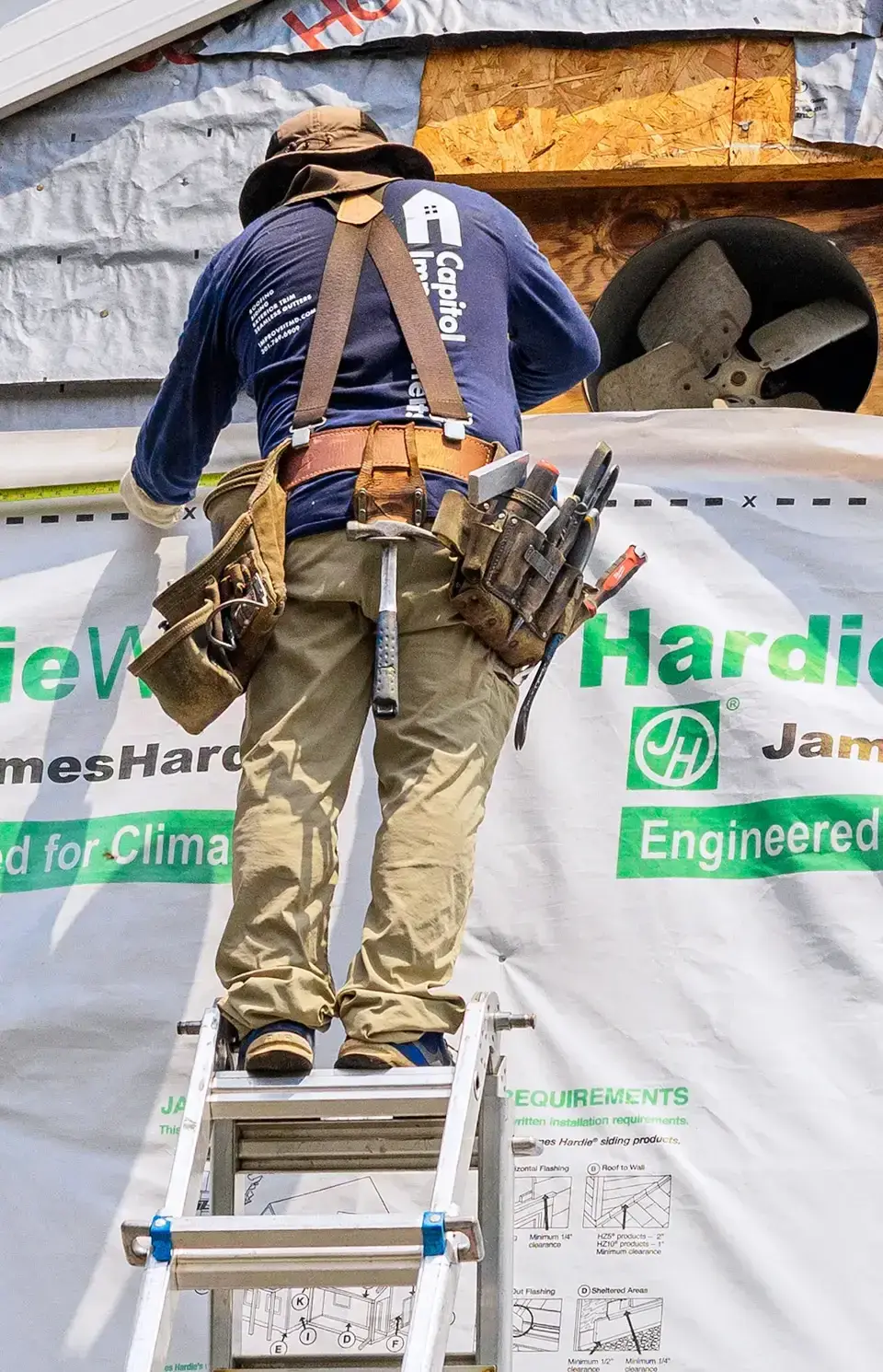 Installing new siding on ladder.
