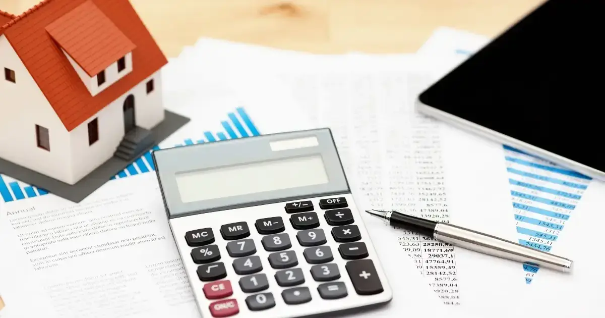 An assortment of roof financing paperwork with a calculator and a model of a home