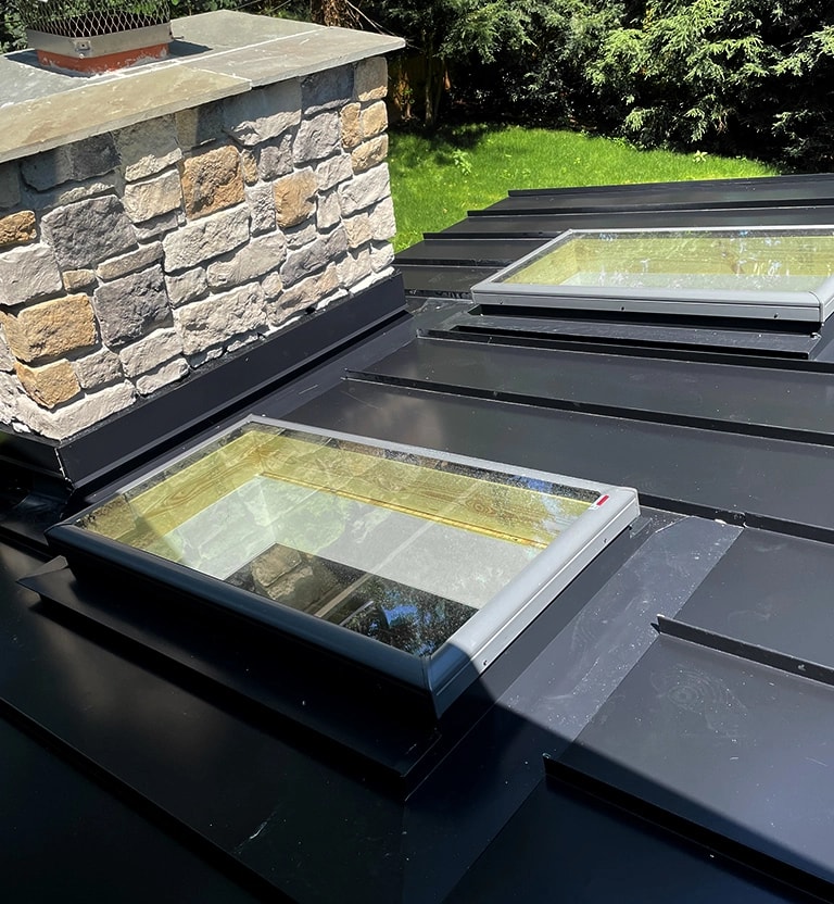 Black standing seam metal roof with 2 skylights and custom fabricated metal flashing. 