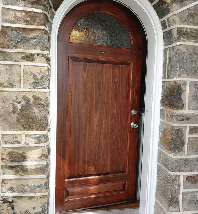 A custom wooden stained half-round hobbit front entry door.