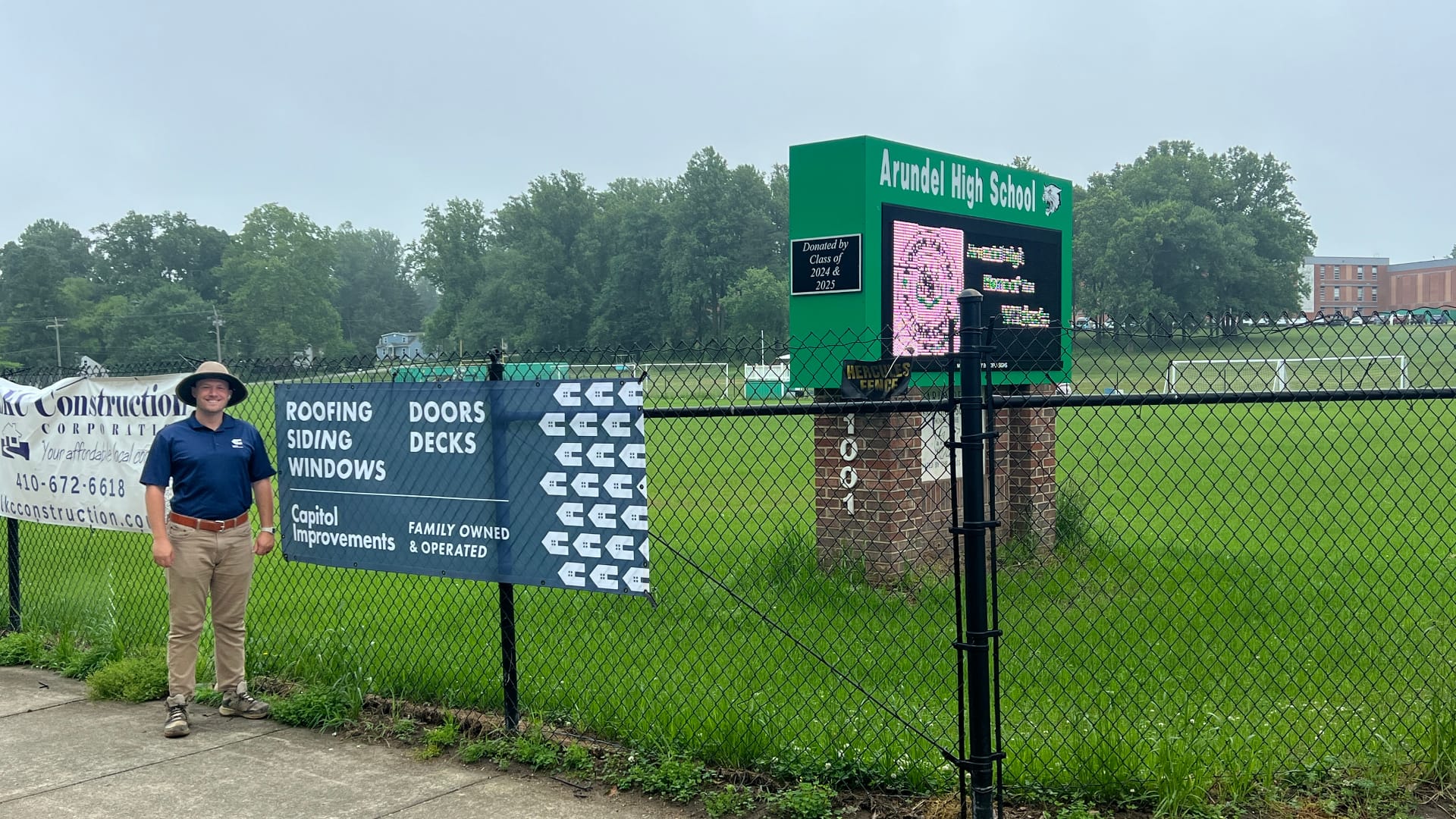 Capitol Improvements team beside sponsor sign at Arundel High School, Gambrills MD